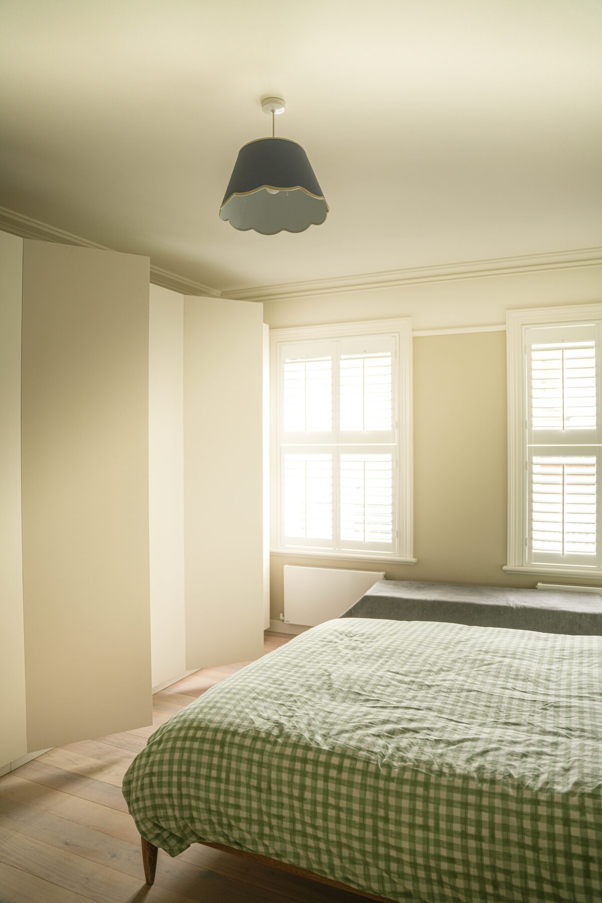Bedroom with green gingham bedding and scalloped pendant