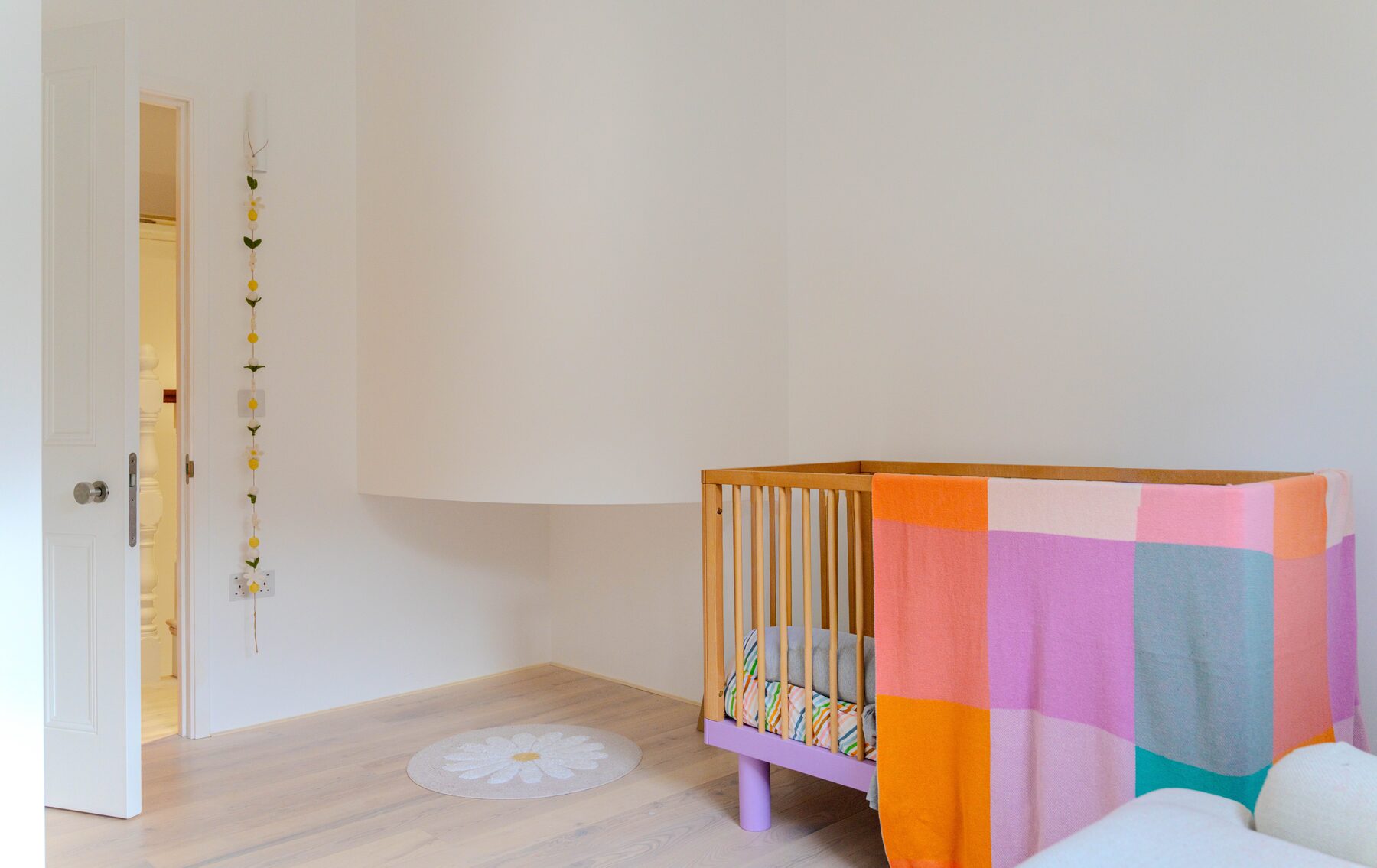 Nursery with colourful cot and curved plasterwork