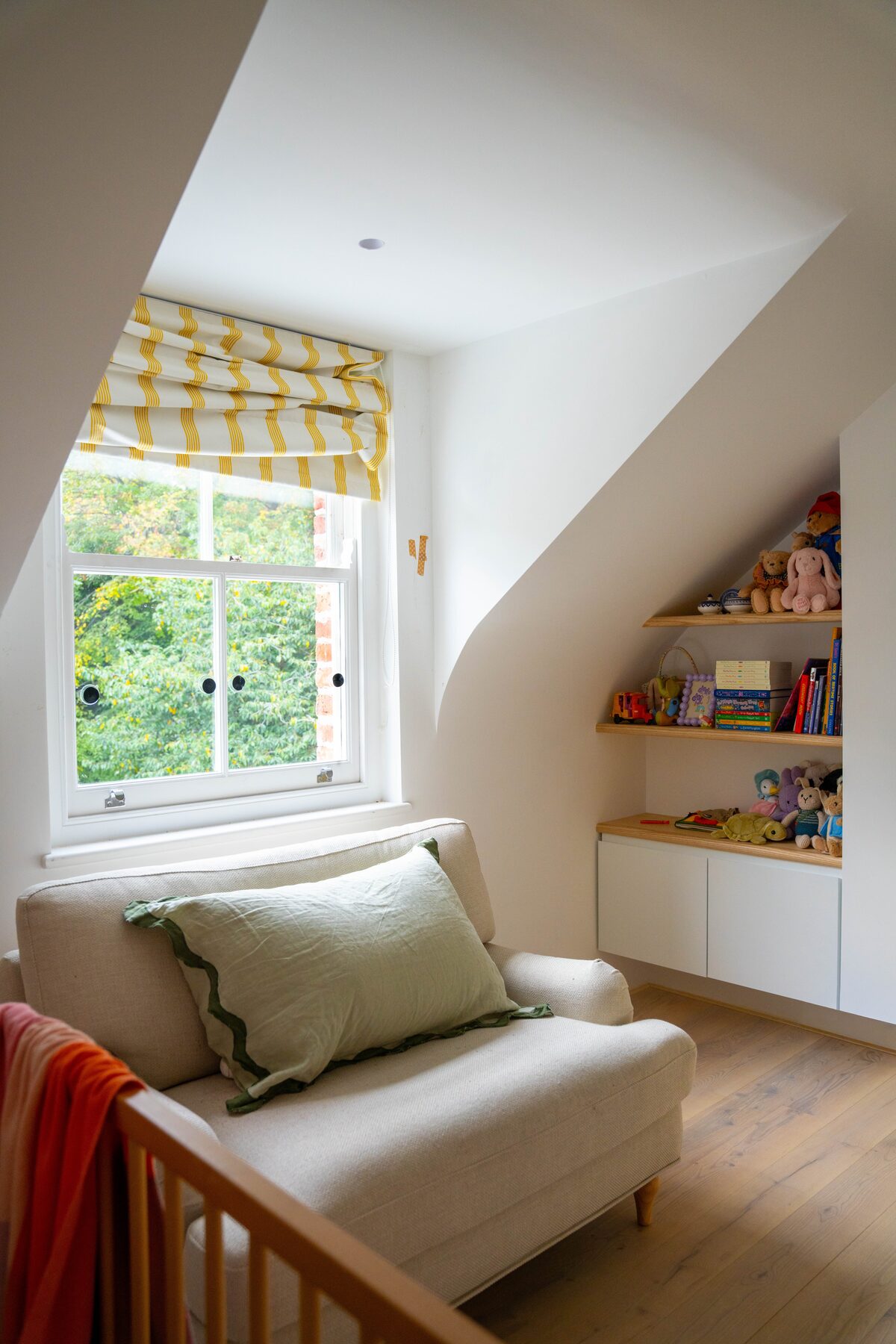 Nursery reading nook with built-in shelving under eaves